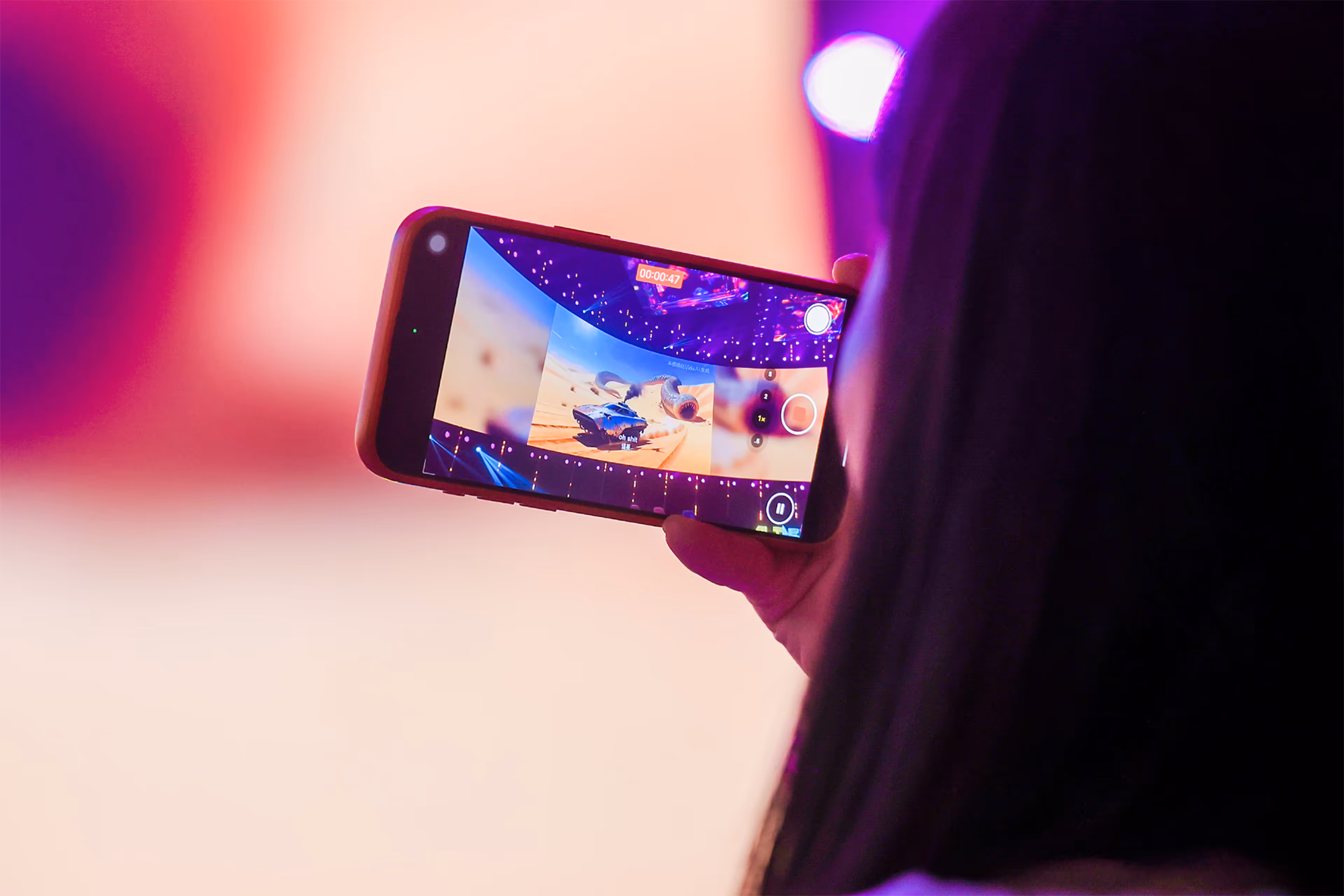 Person holding smartphone recording a colorful stage with desert-themed visuals on screen - at AltNext Edition 1 in 2025.
