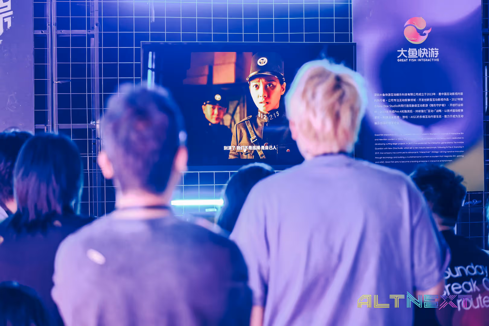 Group of people watching a screen displaying a scene with two uniformed individuals in front of a grid wall with Great Fish Interactive branding - at AltNext Season 1 (2025).
