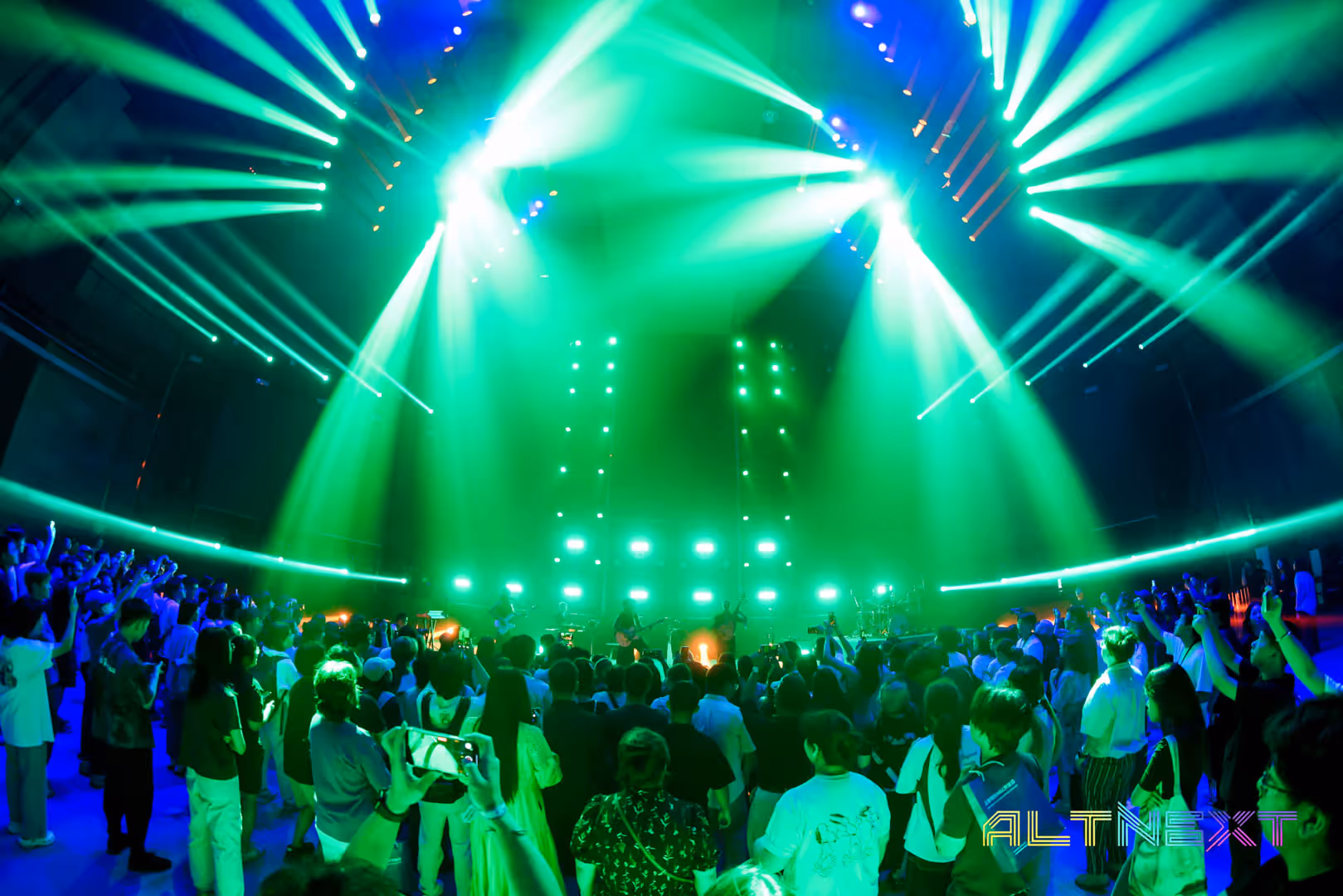 Crowd of people watching a live concert with vibrant green and blue stage lighting and beams - at AltNext Season 1 (2025).