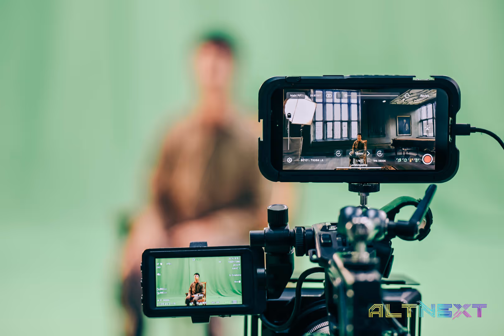 Video camera filming a person sitting against a green screen, with camera screens showing the person in a different indoor setting - at AltNext Season 1 (2025).