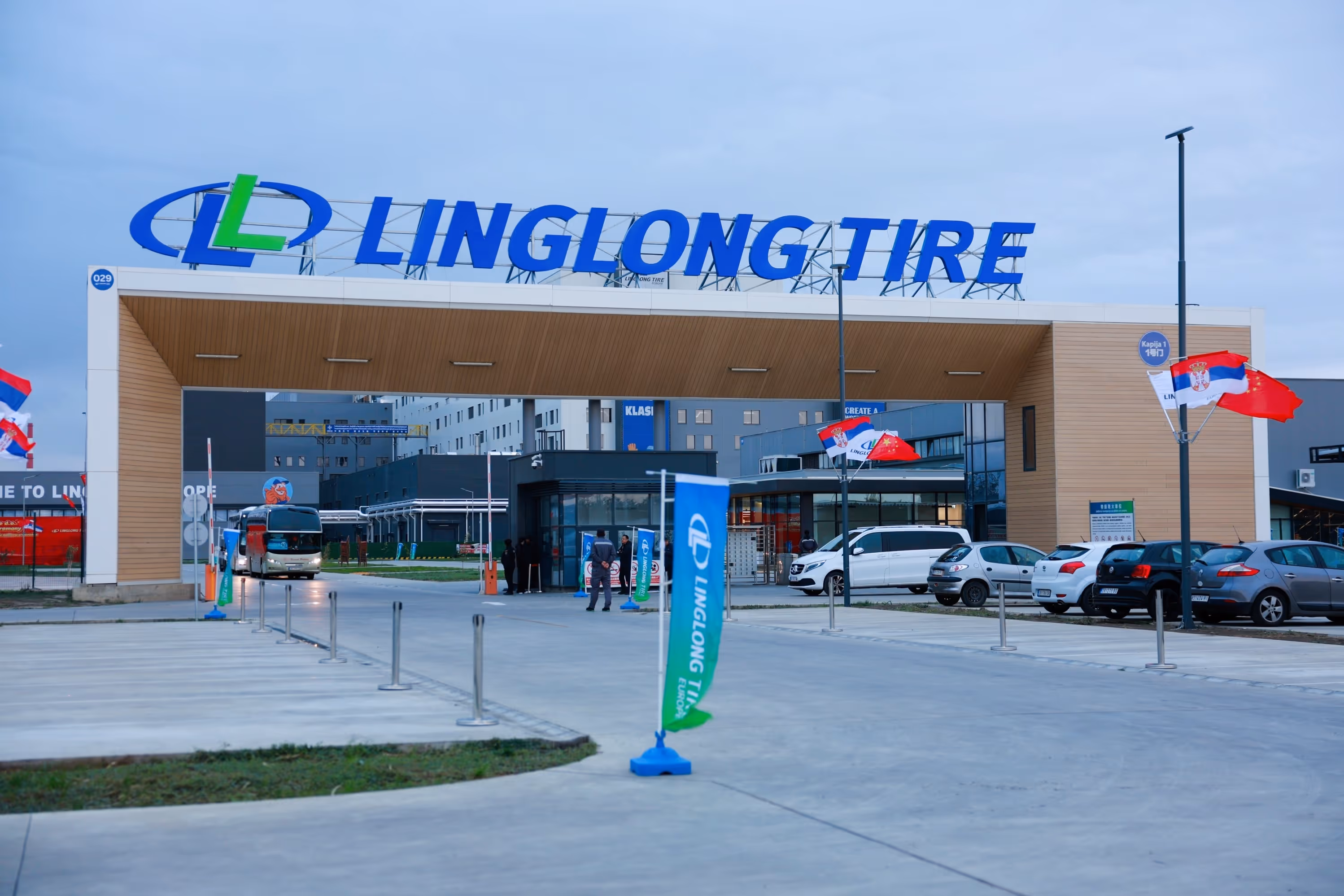 Eingang zur Linglong Tire Fabrik mit Firmenlogo und Flaggen von Serbien und China.
