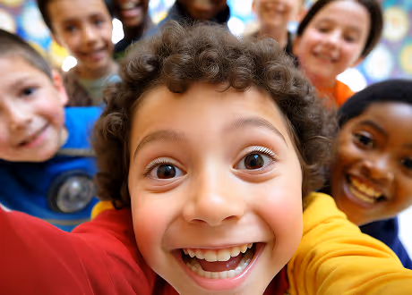 Group of diverse smiling children close together taking a selfie.