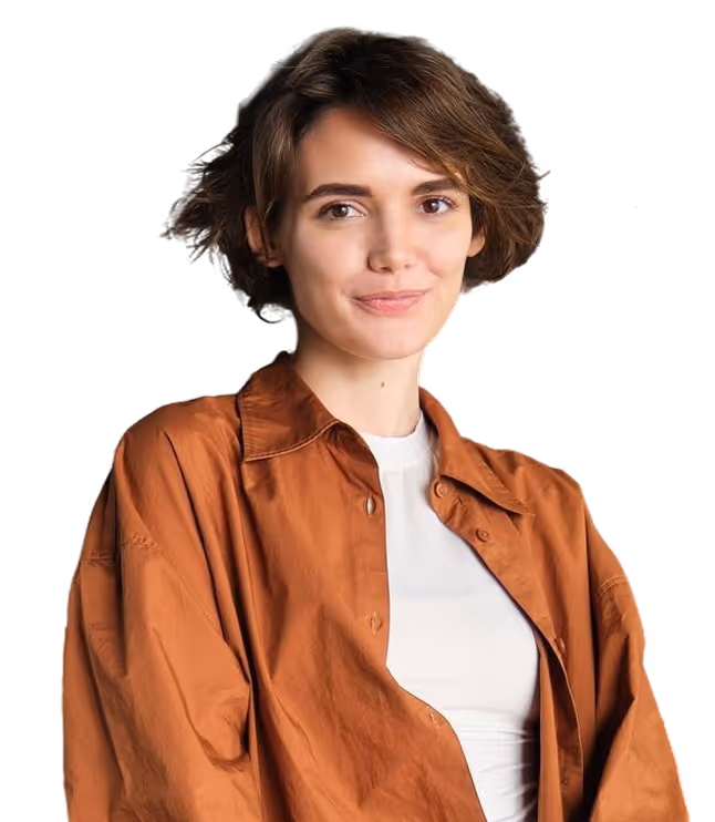 Young woman with short brown hair wearing a white top and an unbuttoned brown shirt smiling slightly.