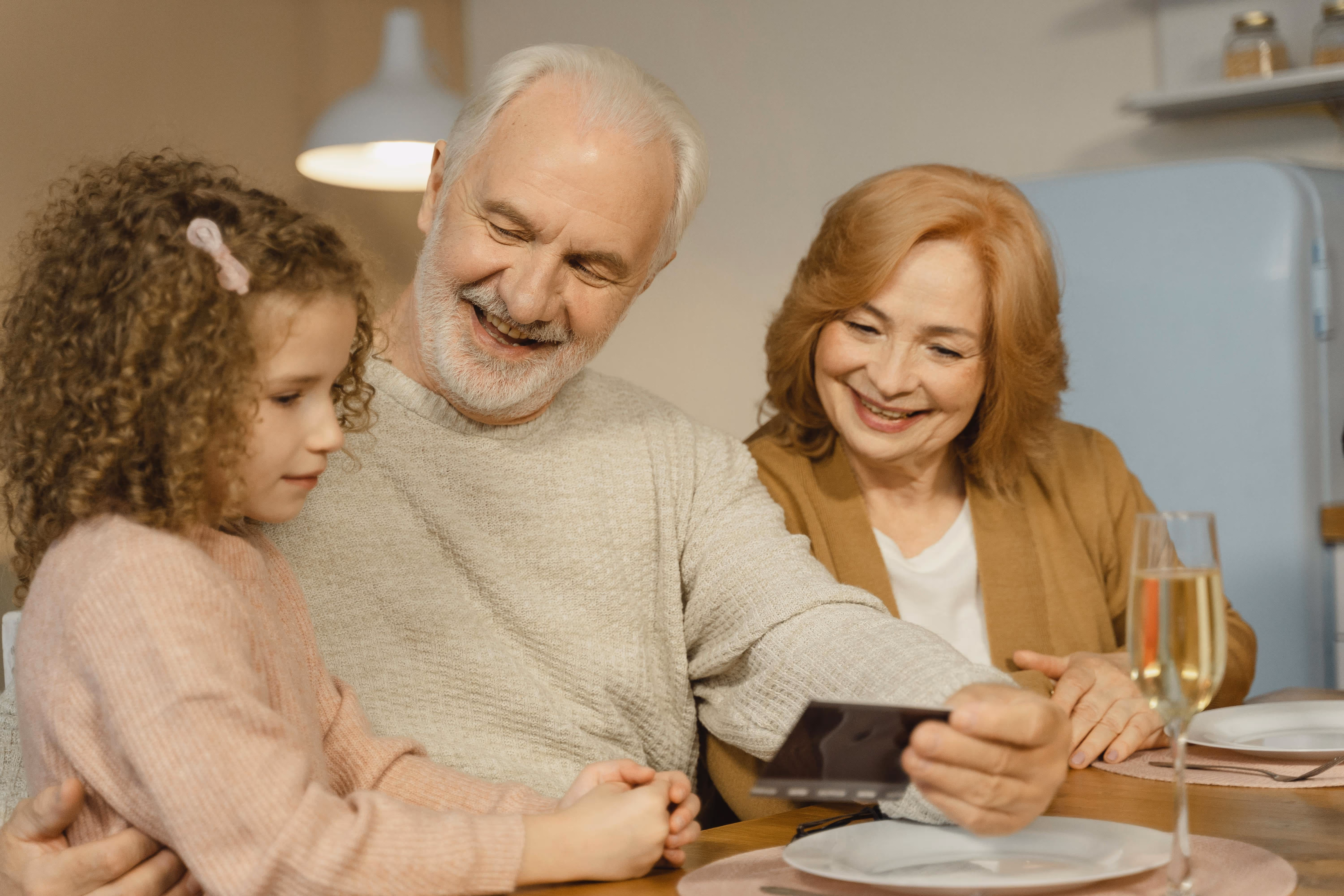 Grandparents spending time with their grandchild at home, looking at a photo together, representing family connection and reunification in Australia.