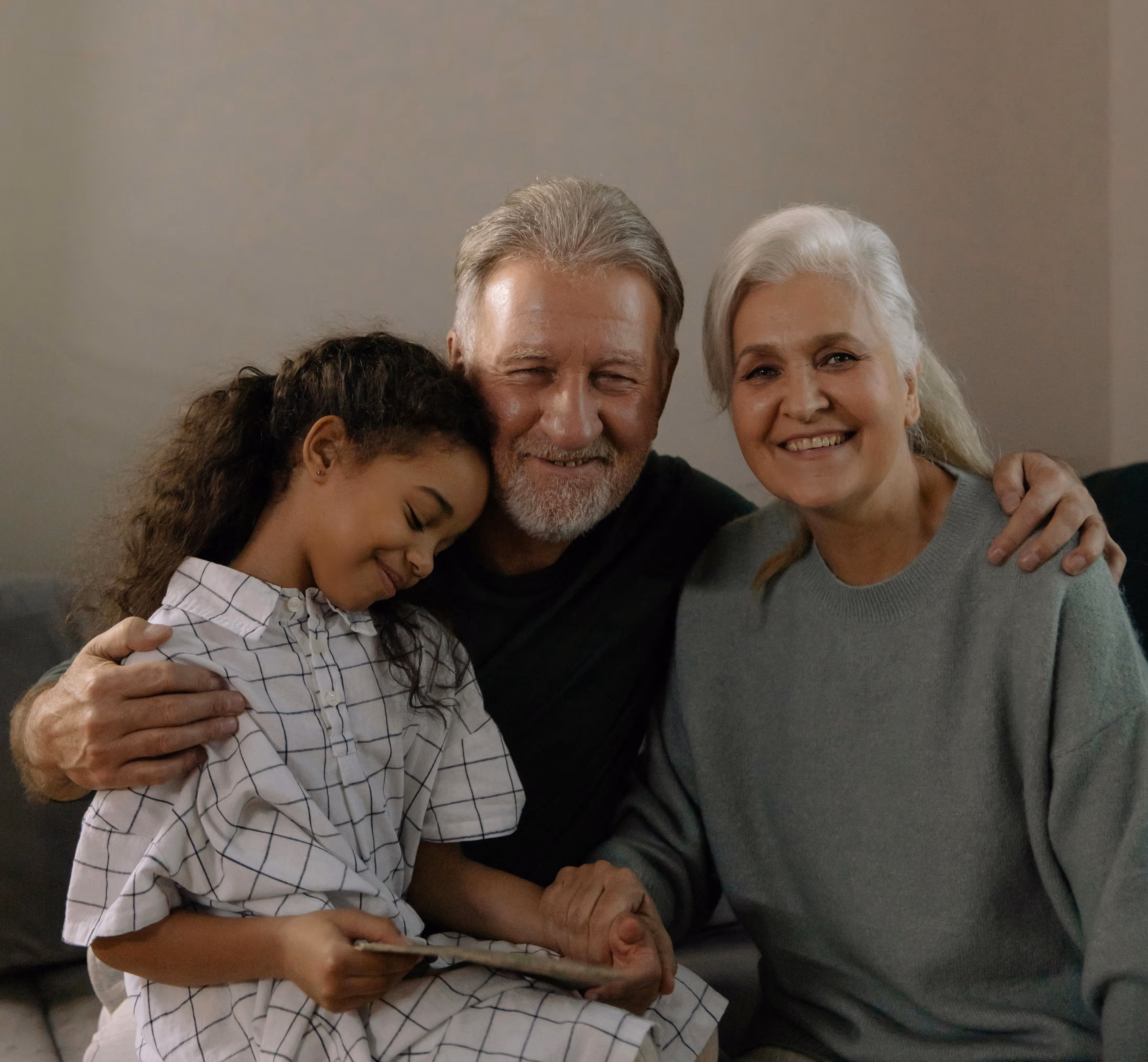 Grandparents sitting with their grandchild at home, sharing a warm moment, representing family connection and reunification in Australia.