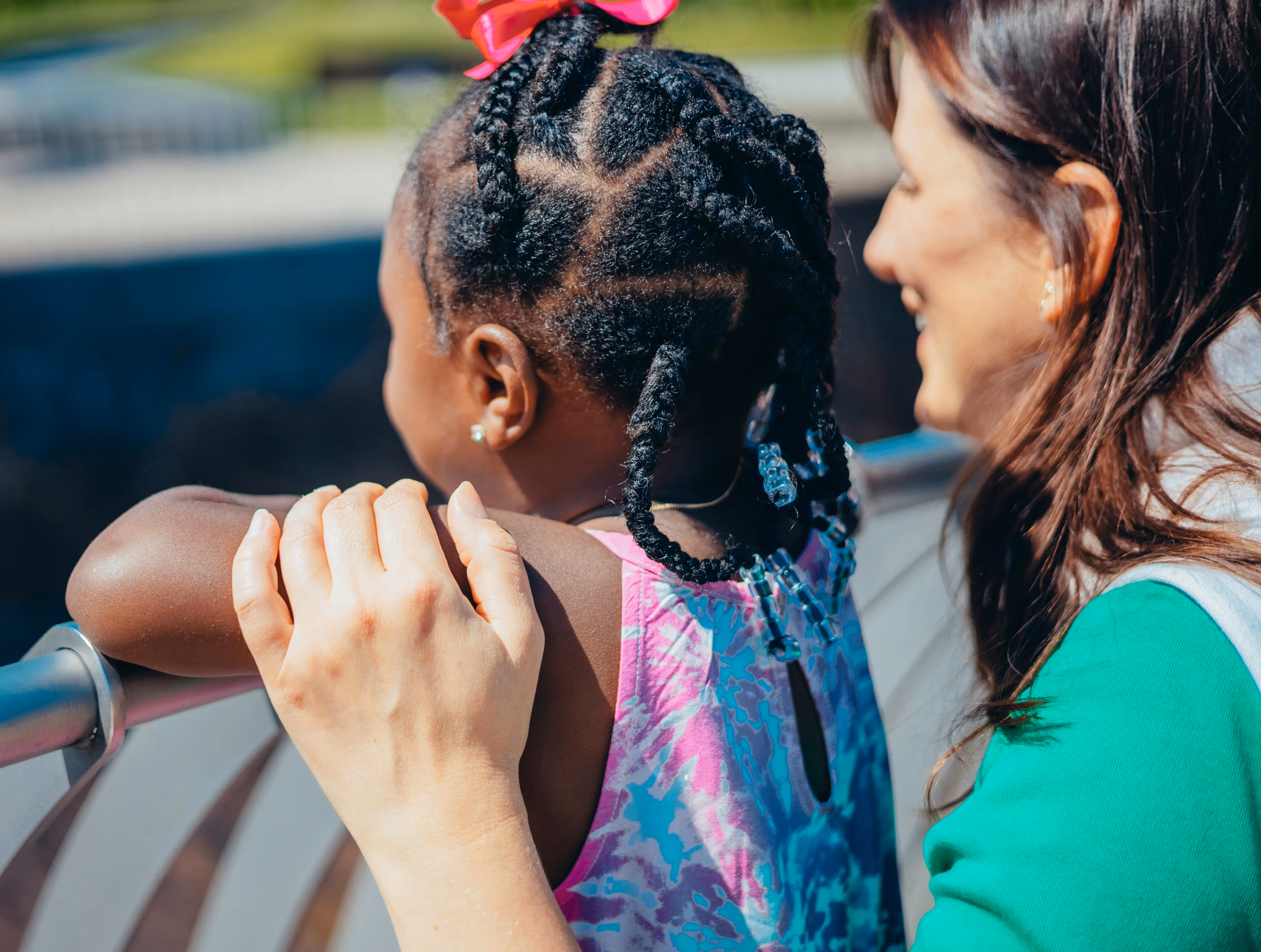 Child standing beside a woman outdoors while looking over a railing for an adoption visa application.