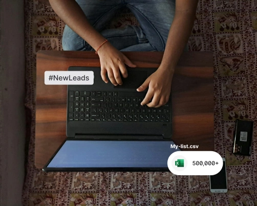 Person typing on a laptop with #NewLeads tag and Excel file icon showing 500,000+ contacts.