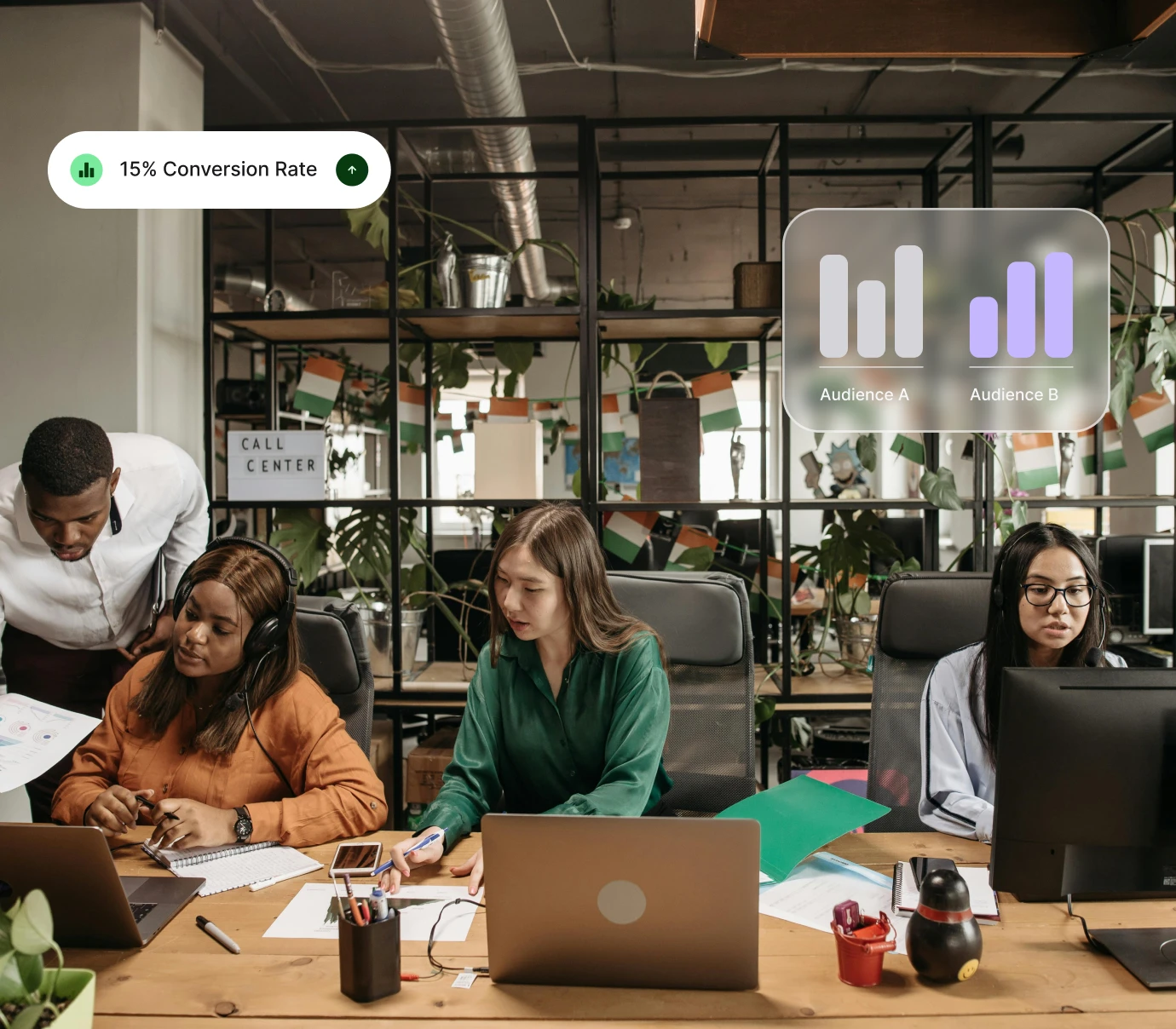 Four diverse call center workers collaborate at desks with laptops and charts in an open office.