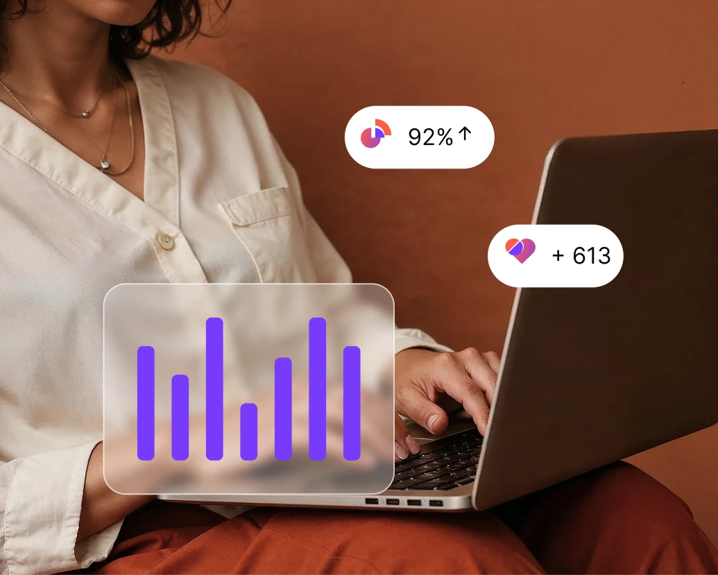 Person in white blouse typing on laptop with purple bar chart and stats overlays on screen.