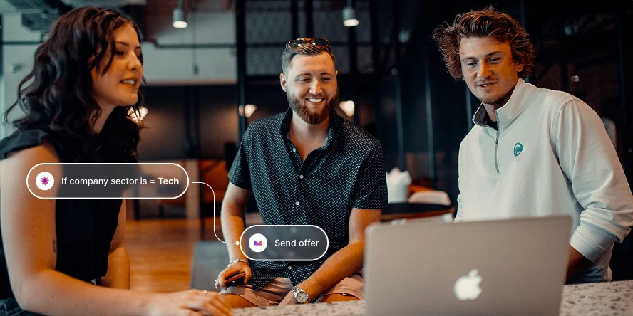 Three people smiling and looking at a laptop screen indoors with workflow tool text overlays.