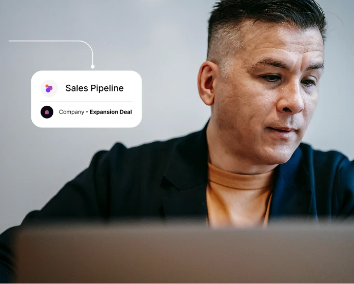 Man sitting behind a laptop with sales pipeline and expansion deal graphic overlay.