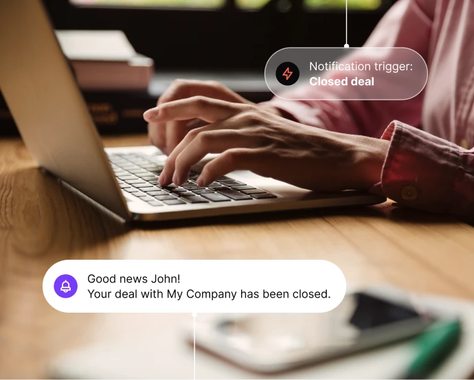Hands typing on a laptop keyboard with notifications about a closed deal.