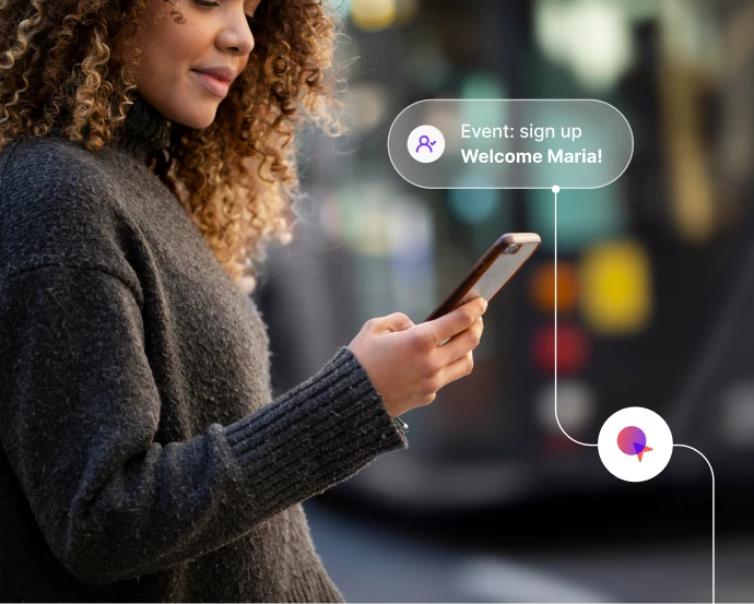 Woman smiling while holding phone with notification: Event signup says Welcome Maria!