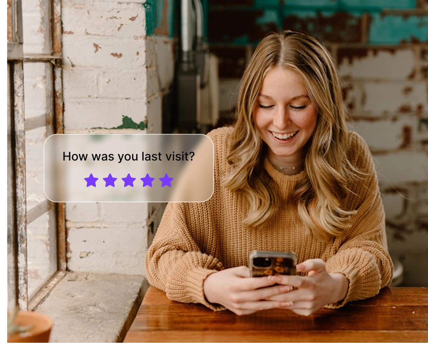 Smiling woman in a brown sweater using her phone with a five-star review prompt on screen.