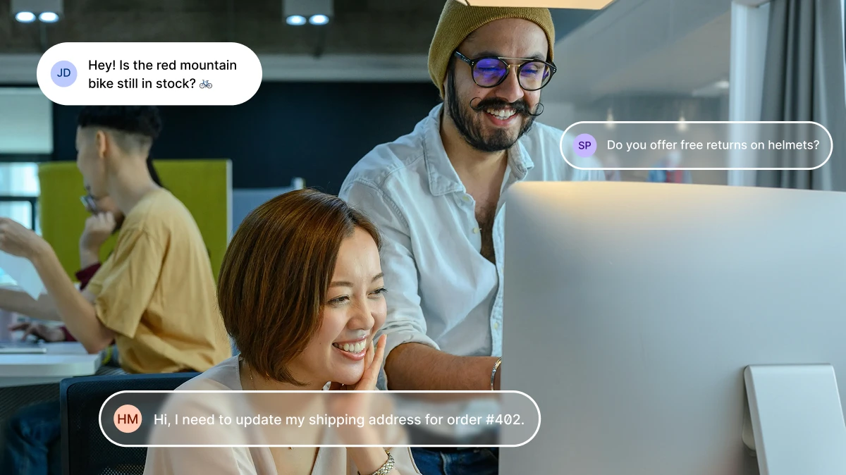 Smiling coworkers looking at a computer with customer chat bubbles about orders and returns.
