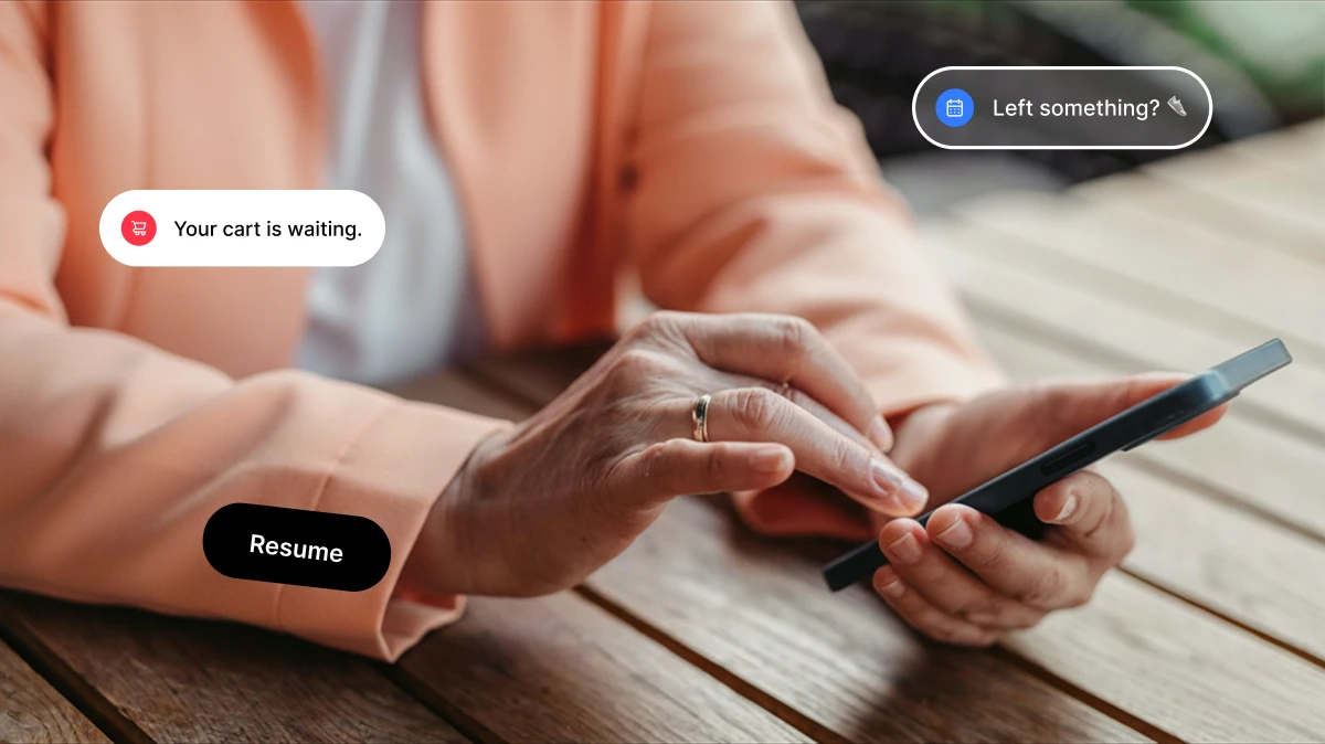 Person in peach jacket using smartphone on wooden table with floating messages about cart and resume.