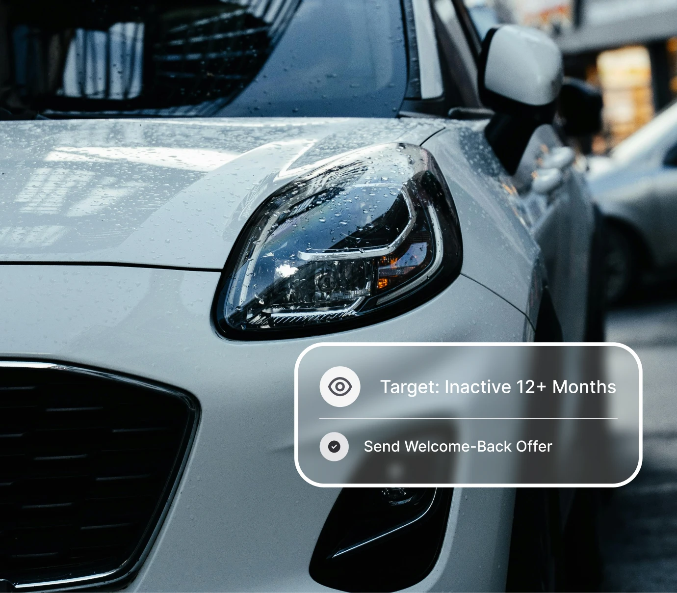 Close-up of a wet white car's front headlight with overlay text about targeting inactive customers 12+ months.