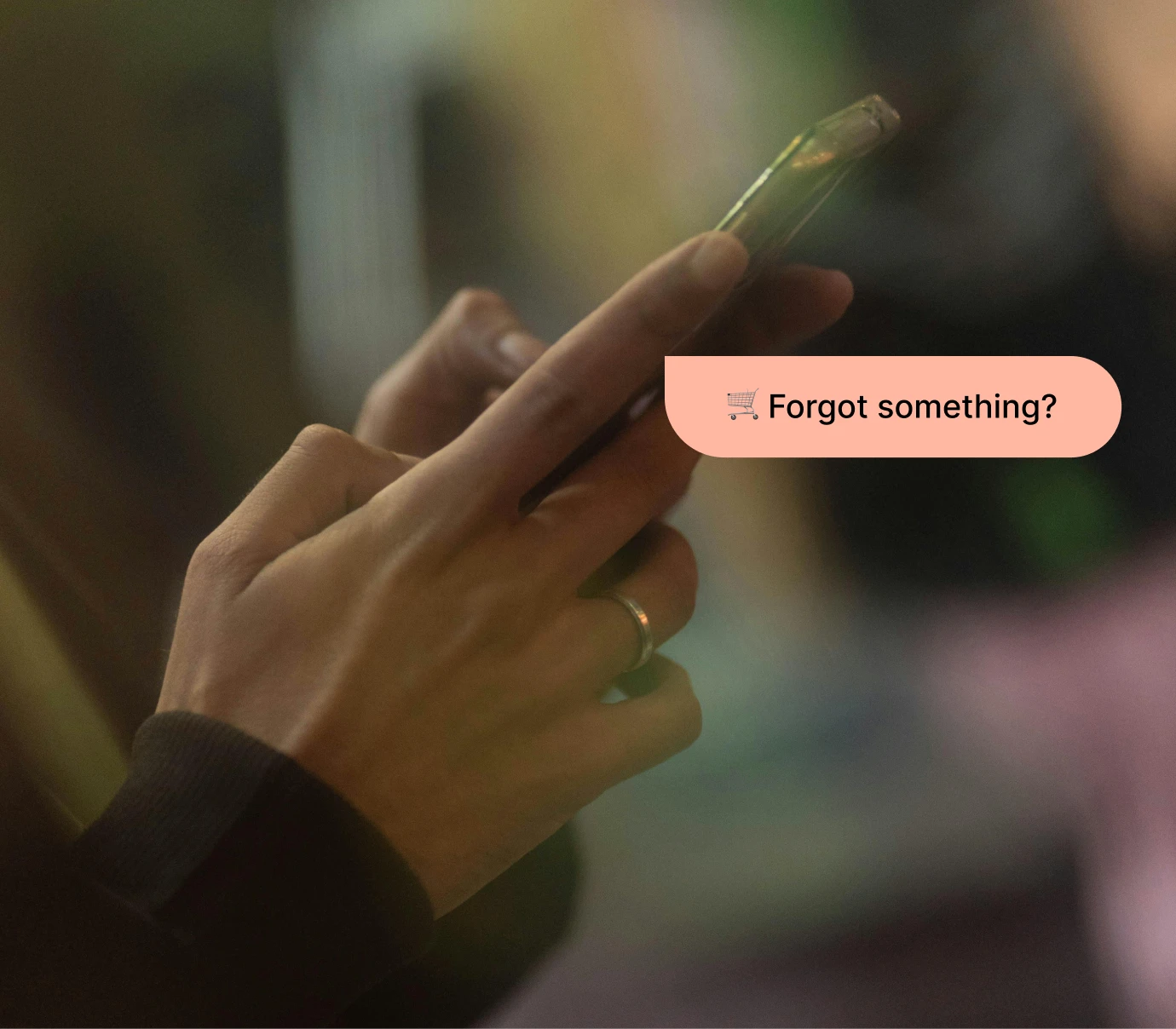 Close-up of hands holding smartphone with a chat bubble saying, 'Forgot something?'