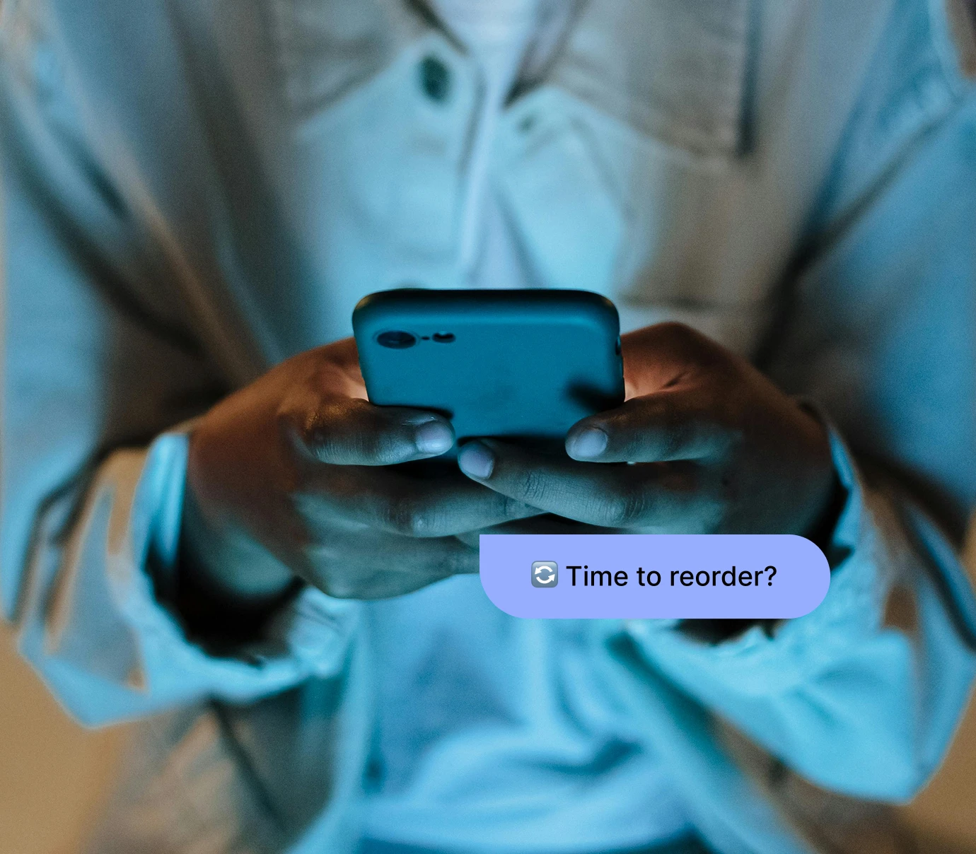 Person holding smartphone with message bubble saying 'Time to reorder?'
