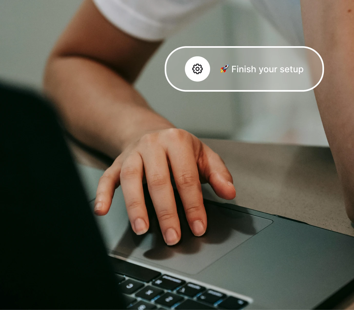 Hand using a laptop trackpad with a popup saying Finish your setup and a settings icon.