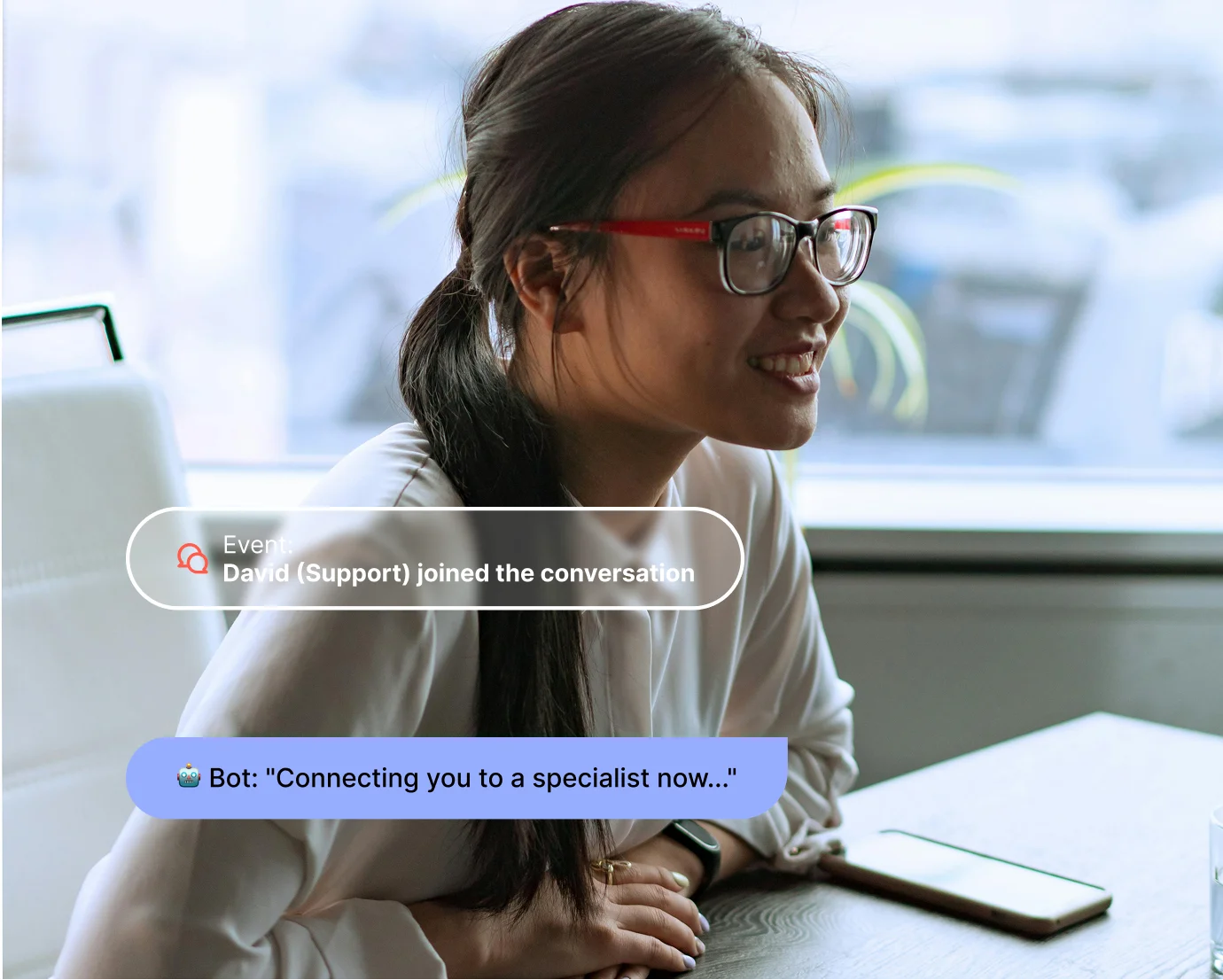 Smiling woman with glasses sitting at a table with phone and chat messages about a support specialist.