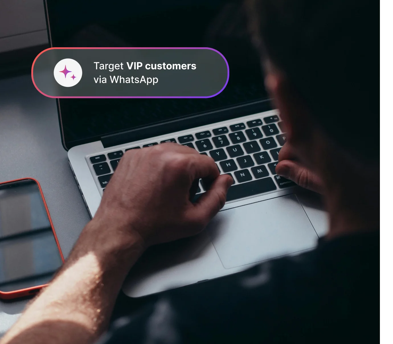 Person typing on laptop keyboard with phone on table and text bubble about targeting VIP customers on WhatsApp.