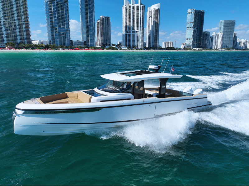 White Saxdor 400 GTS motorboat cruising on blue water near a city skyline with tall buildings.
