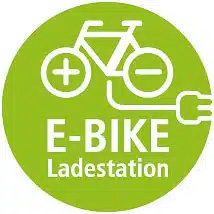 Symbol eines E-Bikes mit Plus- und Minuszeichen auf Rädern und einem Stecker, Text: E-BIKE Ladestation.