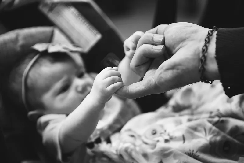 person holding a baby's hand while the baby is in a car seat