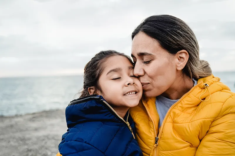 Mother and child in raincoats at the beach