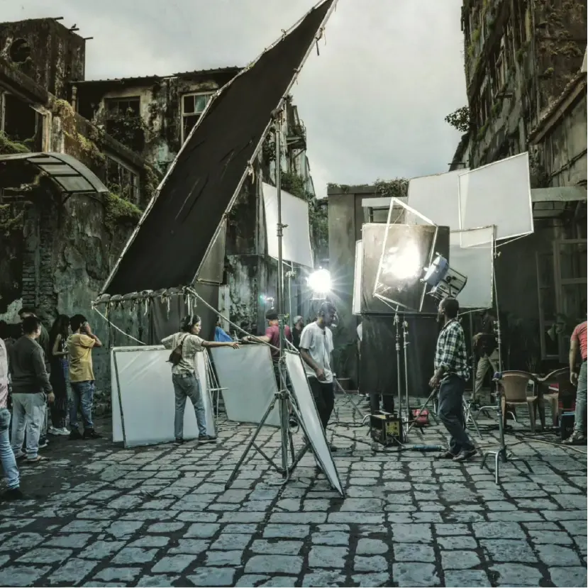A behind-the-scenes look at a film set by Stage5 Production, showing a technical crew, high-end camera equipment, and lighting rigs on a suburban street location.