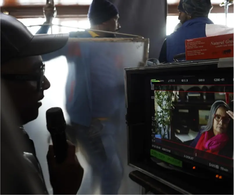 Director Faraz Arif Ansari checking a scene on the monitor for the film Bun Tikki; the screen shows a close-up of actress Shabana Azmi in character.