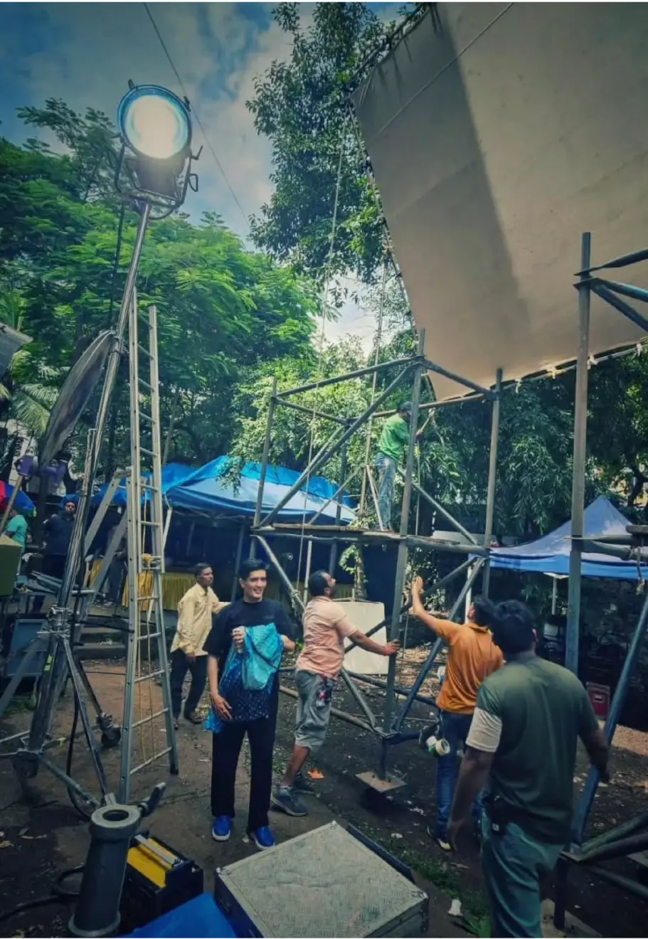 Producer Manish Malhotra on the active film production set of a Stage5 Production, surrounded by crew members, scaffolding, and professional lighting equipment.