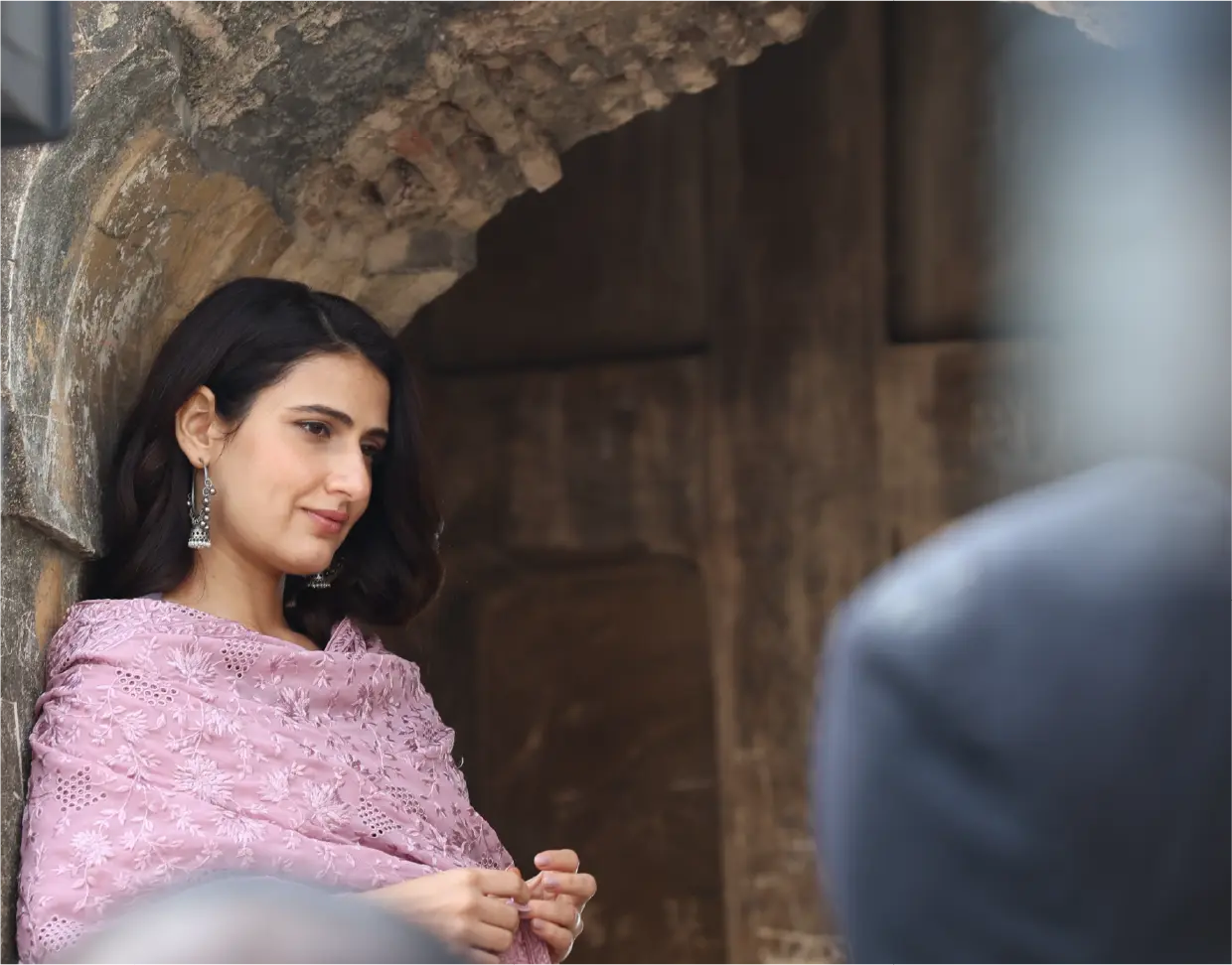 Fatima Sana Shaikh as Minni in a production still from Gustaakh Ishq; she is wearing a light purple embroidered dupatta and leaning against an ancient stone archway.