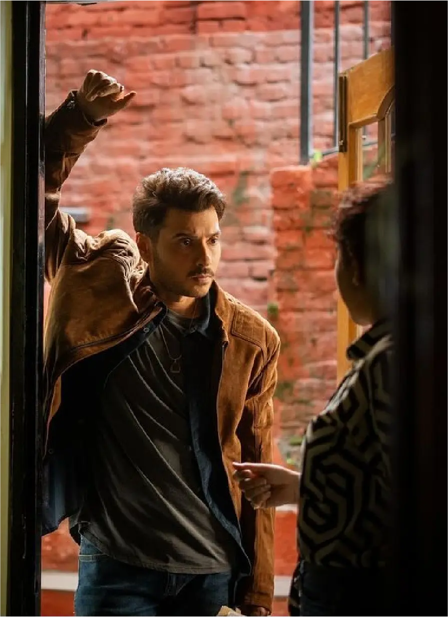 Actor Divyenndu leaning against a doorway in a brown suede jacket during a dramatic scene for the movie Saali Mohabbat.