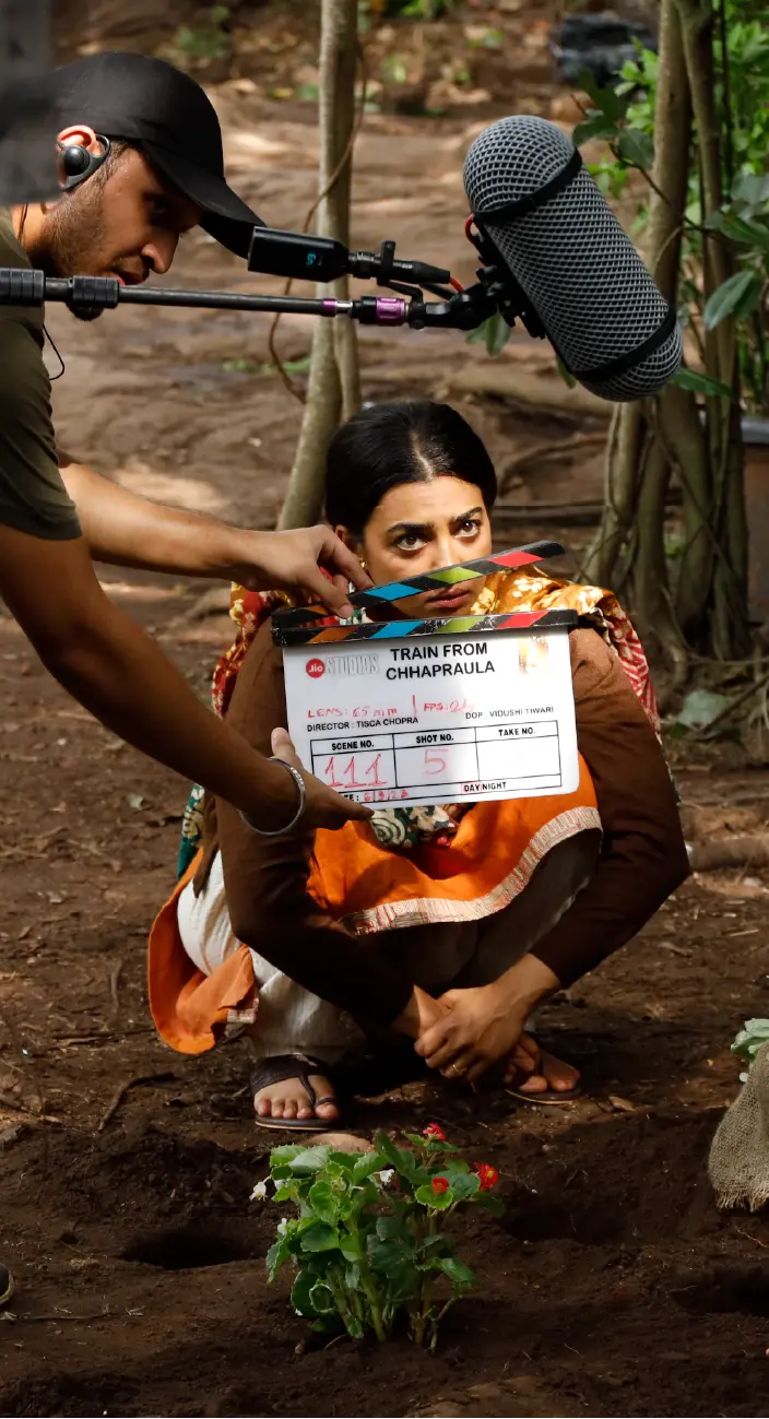 Behind-the-scenes shot of Radhika Apte in a rustic setting with a clapperboard for the film Saali Mohabbat.