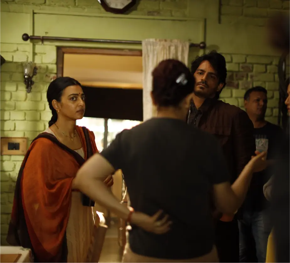 Actors Radhika Apte and Anshumaan Pushkar in discussion with director Tisca Chopra on the dimly lit indoor set of Saali Mohabbat.
