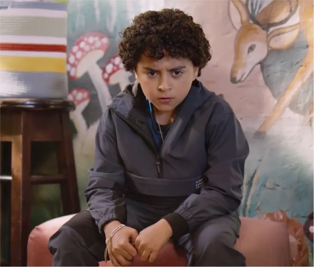 Young actor Rohaan Singh with an intense, frowning expression sitting in front of a wall painted with deer and mushrooms on the set of Bun Tikki.