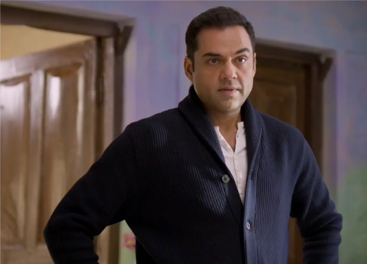 Actor Abhay Deol looking contemplative while standing in a room with wooden doors on the set of Bun Tikki.