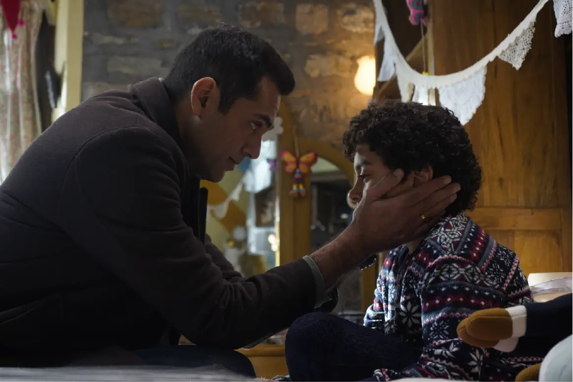 Abhay Deol as Sidhant holding young Rohaan Singh (Shanu) by the face in a tender, emotional scene from the movie Bun Tikki.