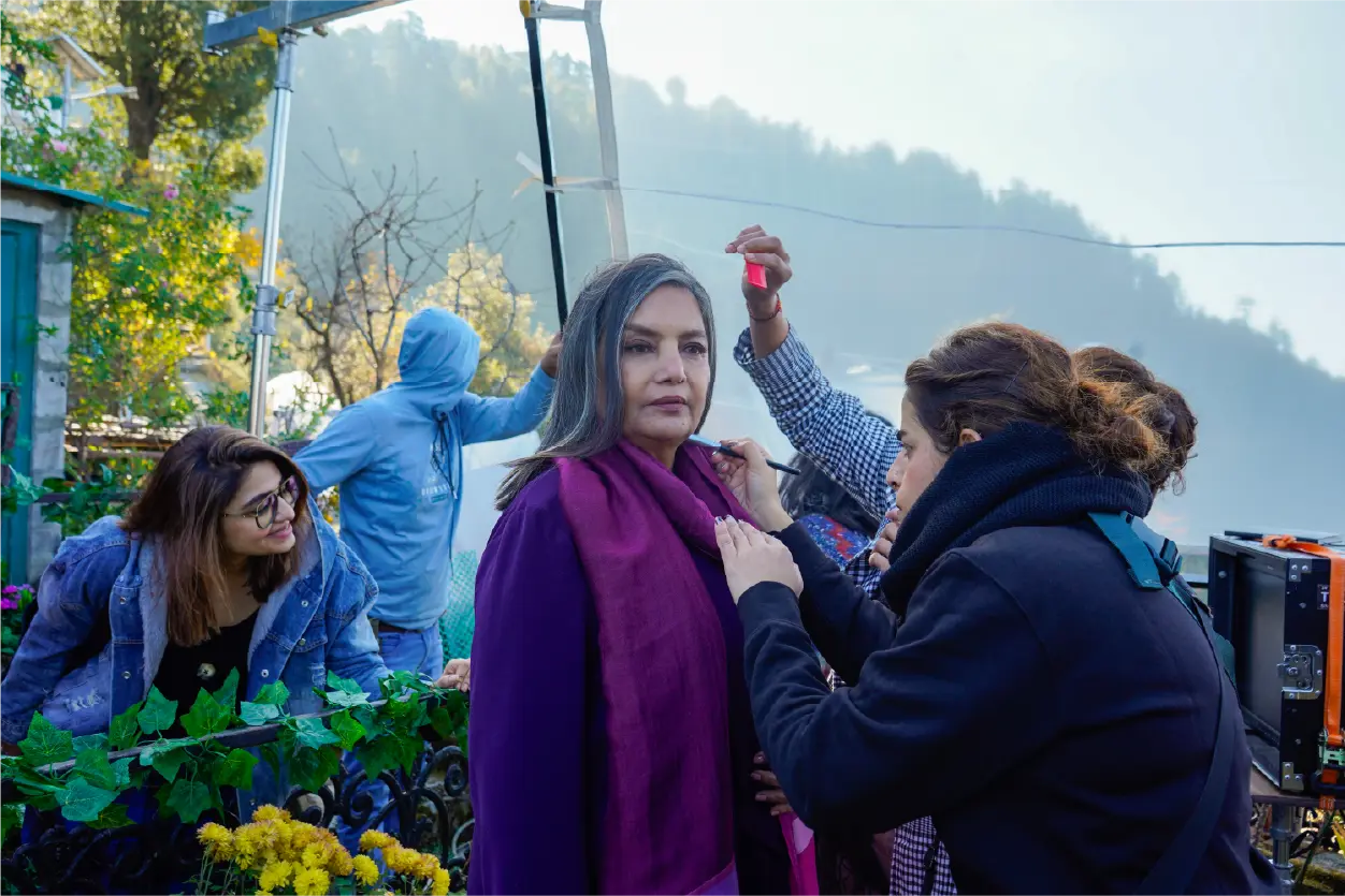 Behind-the-scenes production still of Shabana Azmi in a purple outfit during a hair and makeup session on the Bun Tikki film set.