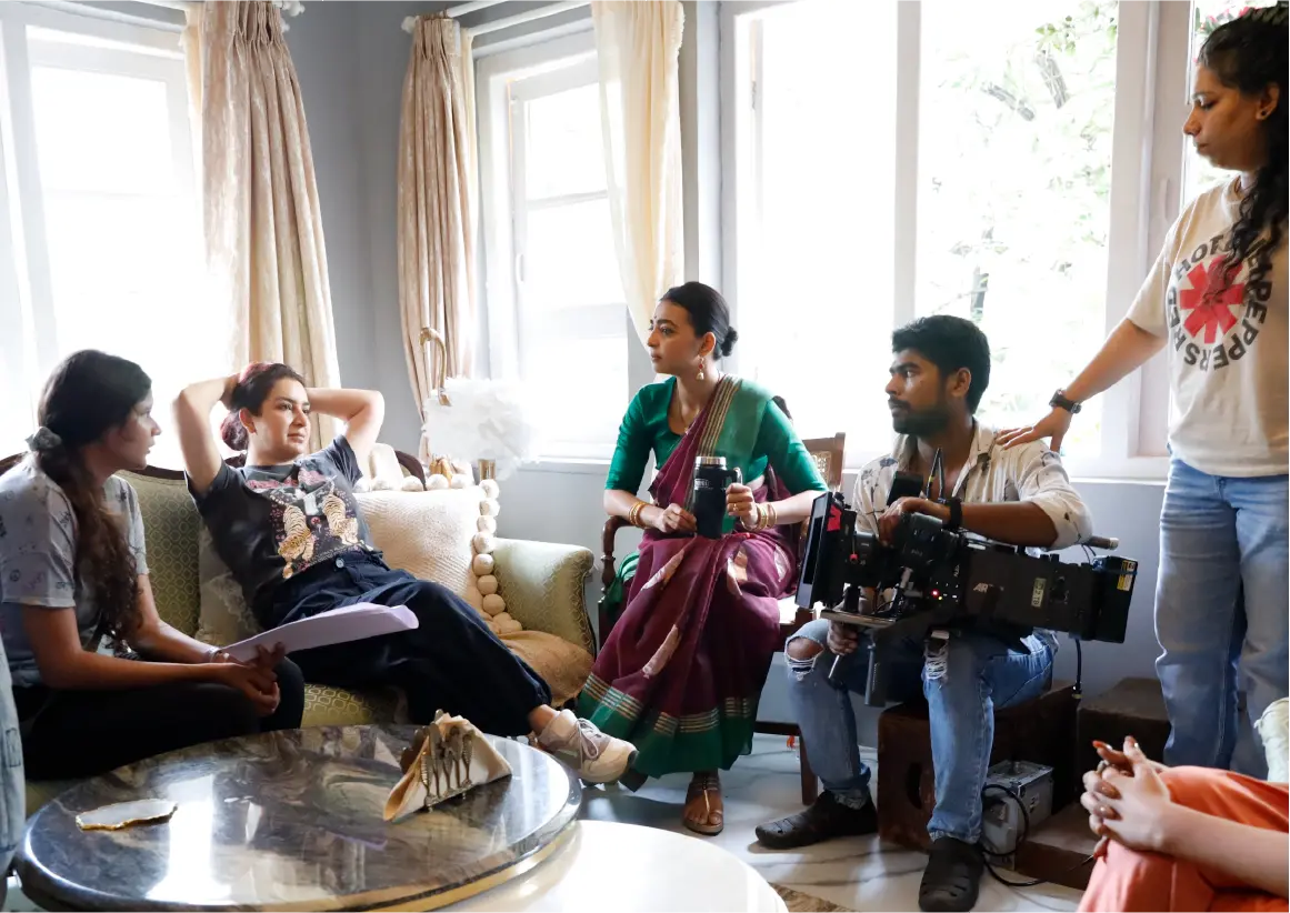 A BTS still from saali mohabbat featuring Radhika Apte and Tisca Chopra having a conversation while the film crew looks on.