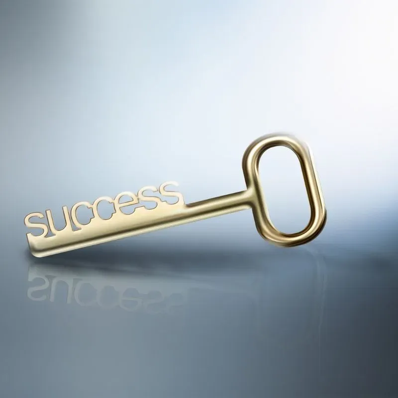 Golden key with the word "success" embossed on it, reflecting on a surface.