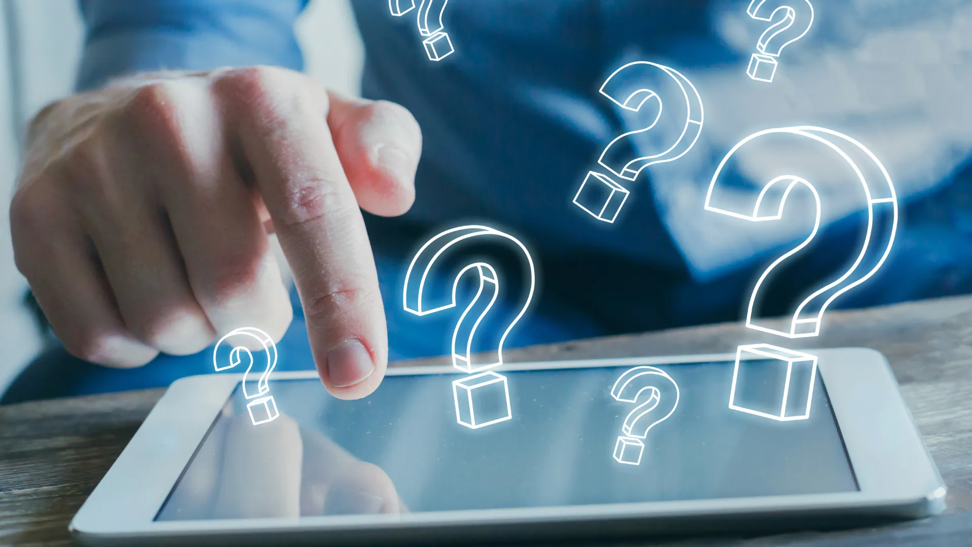A man is pointing at a tablet with question marks on it.