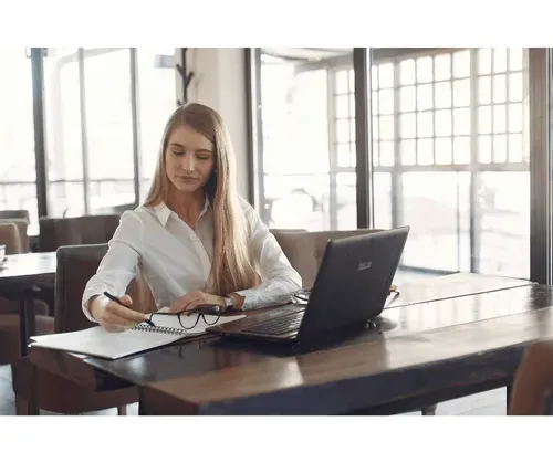 A woman sitting at a table with a laptop and a notebook.
