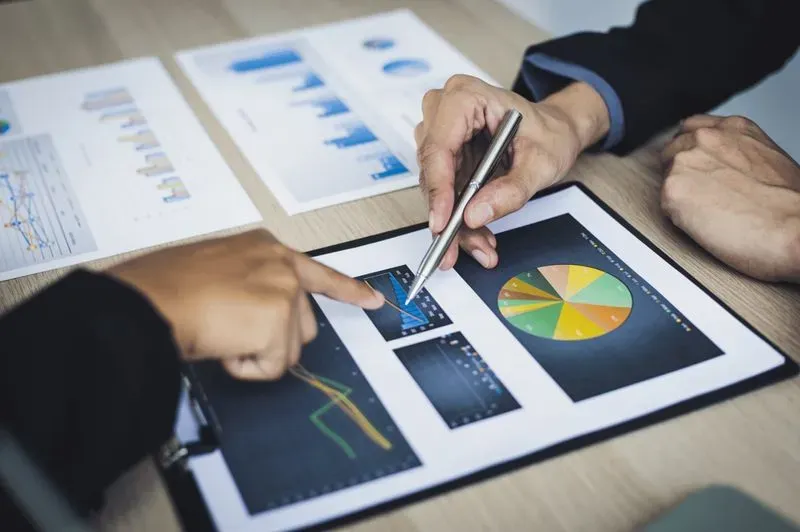 Two business people looking at graphs on a clipboard.