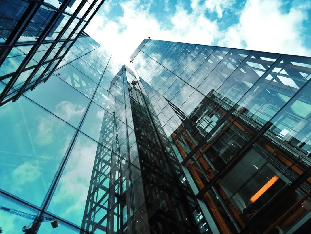 Office building skyscrapers reflected in glass with blue skies.