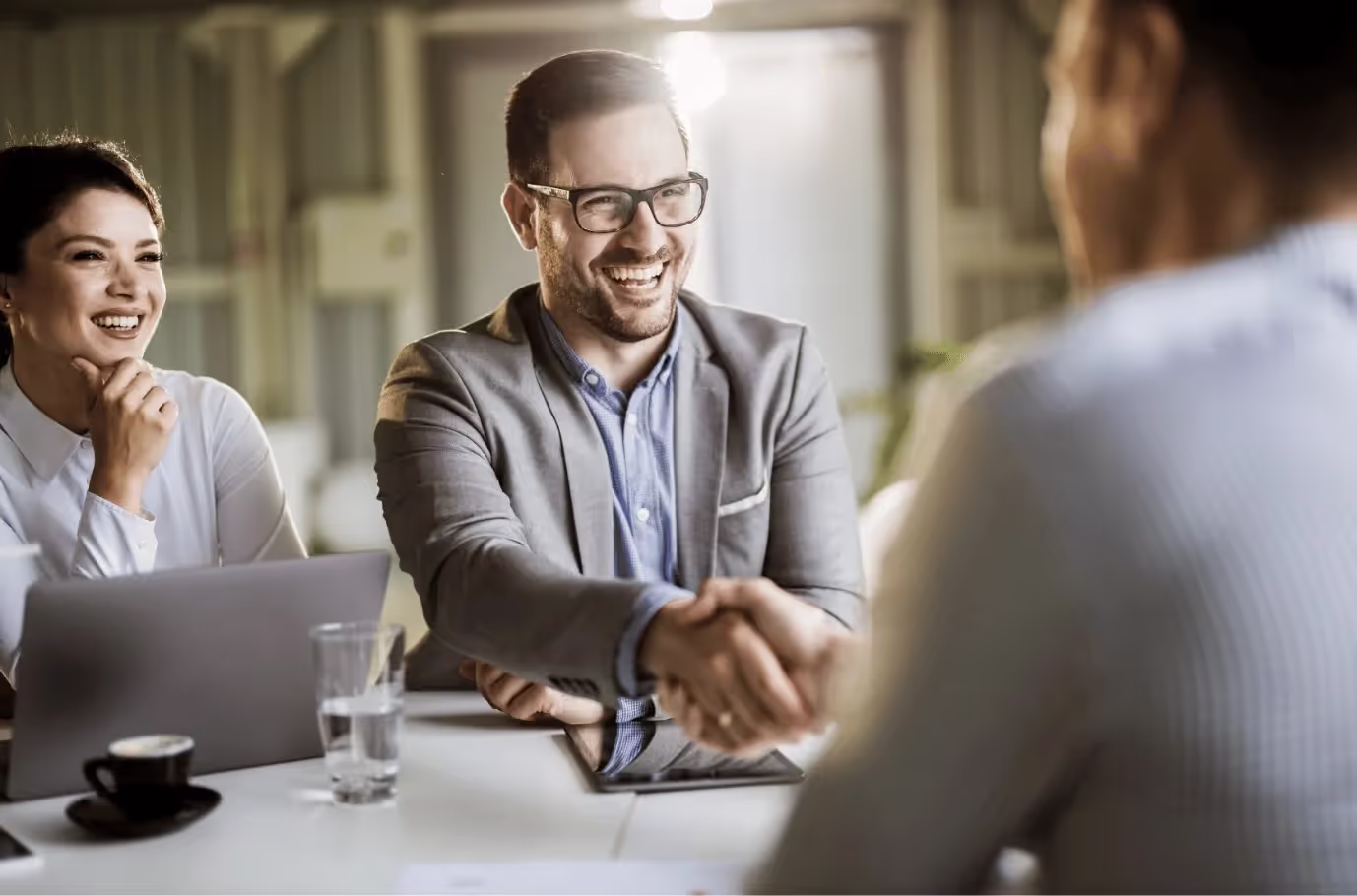 Two business brokers and a client are shaking hands at a meeting.