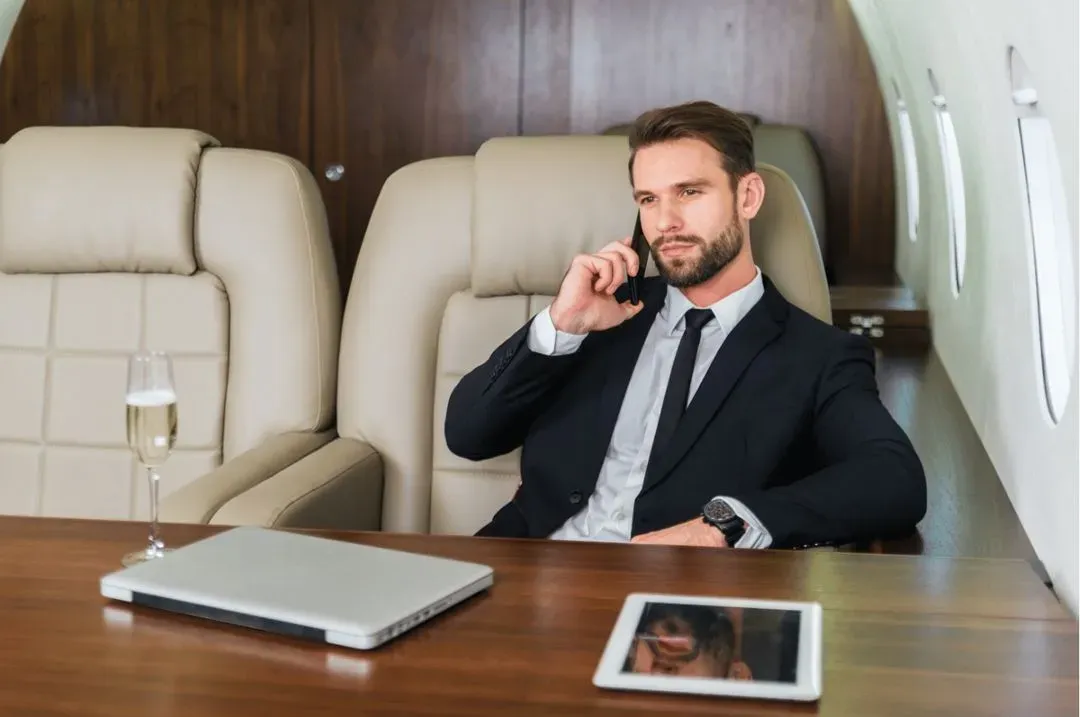 A man in a suit is talking on his cell phone in a private jet.