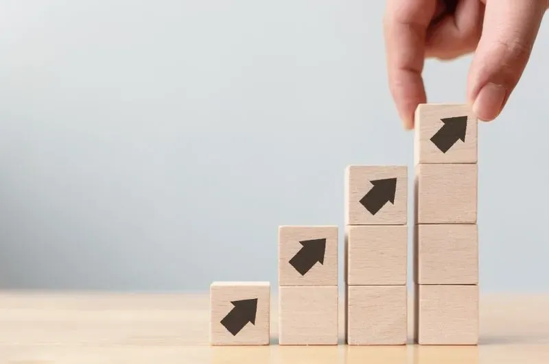 A hand holding wooden blocks with arrows pointing up and down.